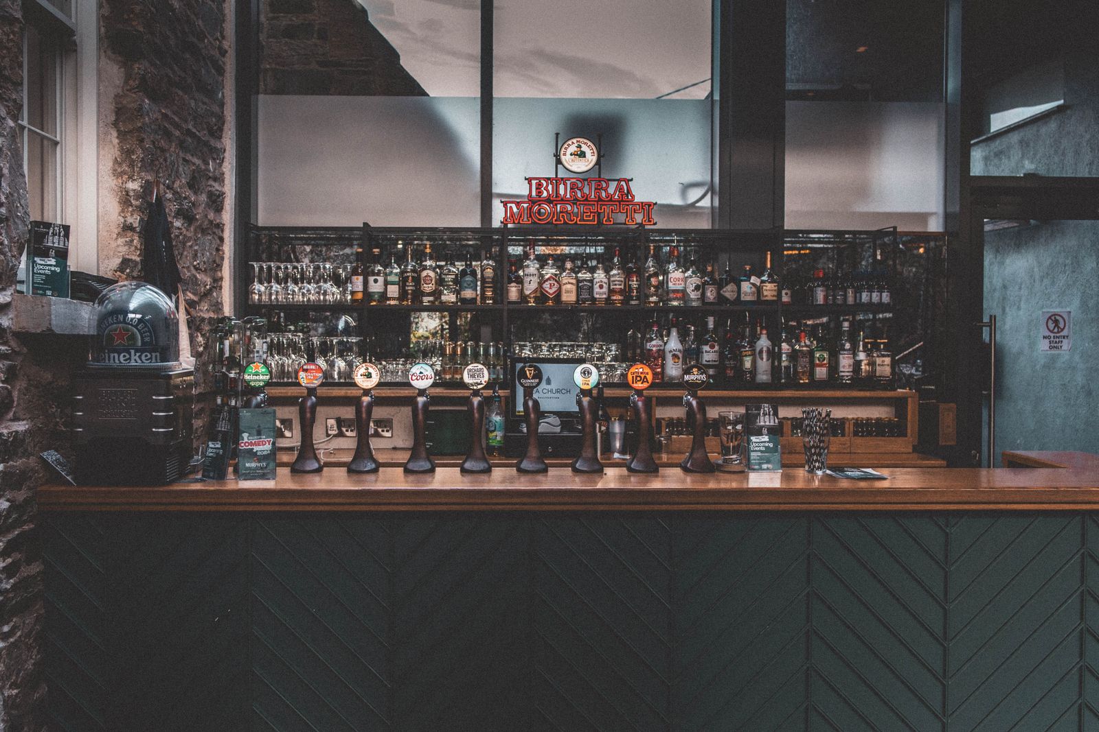 A rustic corner of the pub with a stone wall and a fully stocked bar