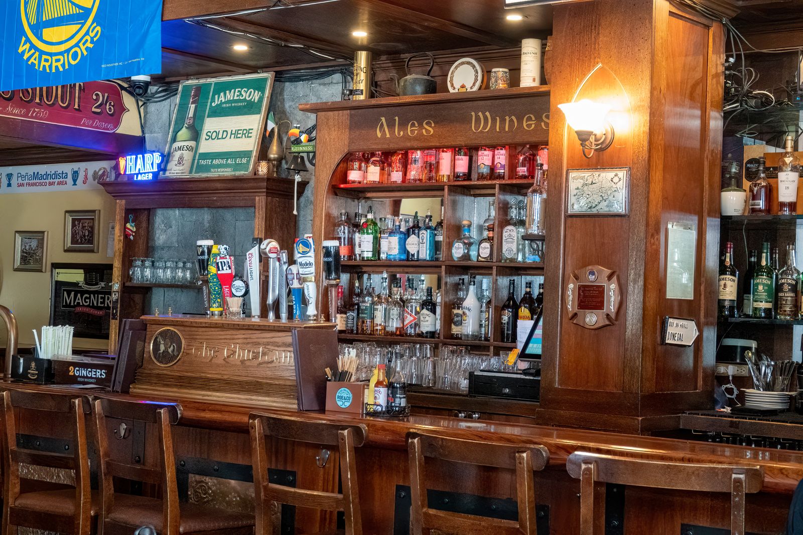 Clancy's back bar lined with bottles under hand-painted ale and wine signs